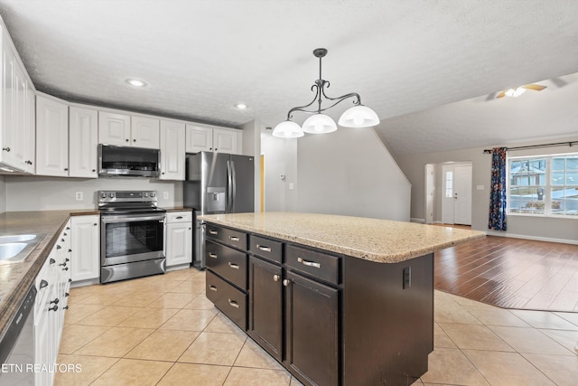 kitchen featuring hanging light fixtures, stainless steel appliances, white cabinetry, and light tile patterned floors