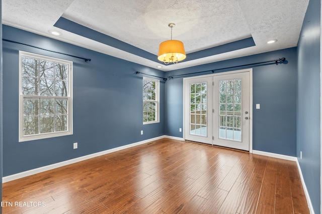 spare room with hardwood / wood-style flooring, a raised ceiling, and a textured ceiling