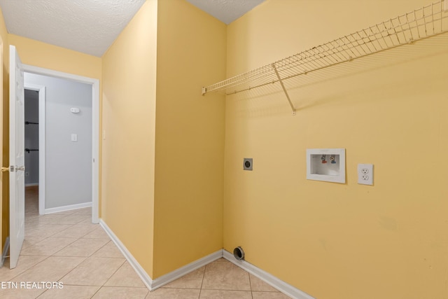 clothes washing area featuring tile patterned flooring, hookup for a washing machine, hookup for an electric dryer, and a textured ceiling