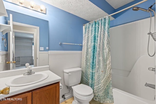 full bathroom featuring toilet, vanity, a textured ceiling, and shower / tub combo with curtain