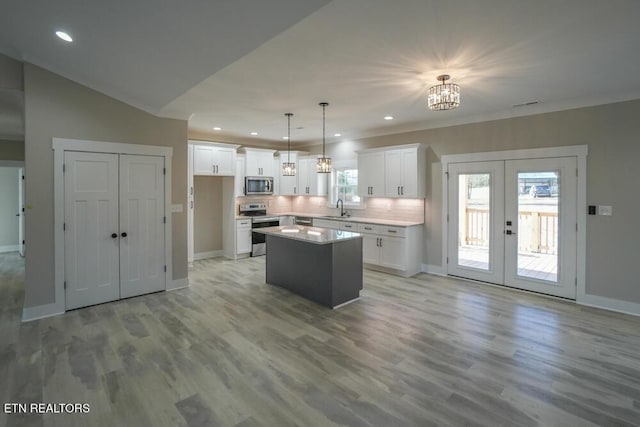 kitchen with french doors, white cabinets, hanging light fixtures, appliances with stainless steel finishes, and a kitchen island