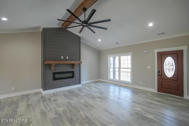 unfurnished living room featuring light wood-type flooring, ornamental molding, ceiling fan, lofted ceiling with beams, and a fireplace