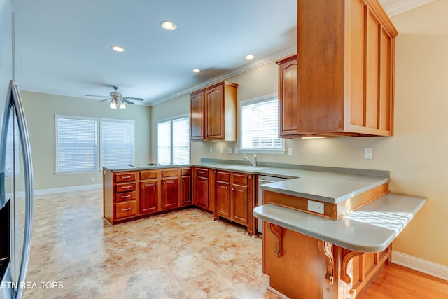 kitchen featuring sink, ceiling fan, ornamental molding, kitchen peninsula, and stainless steel appliances