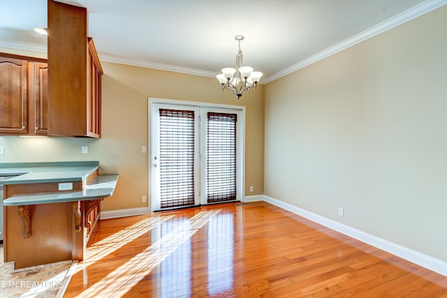 unfurnished dining area featuring crown molding, a chandelier, and light hardwood / wood-style floors