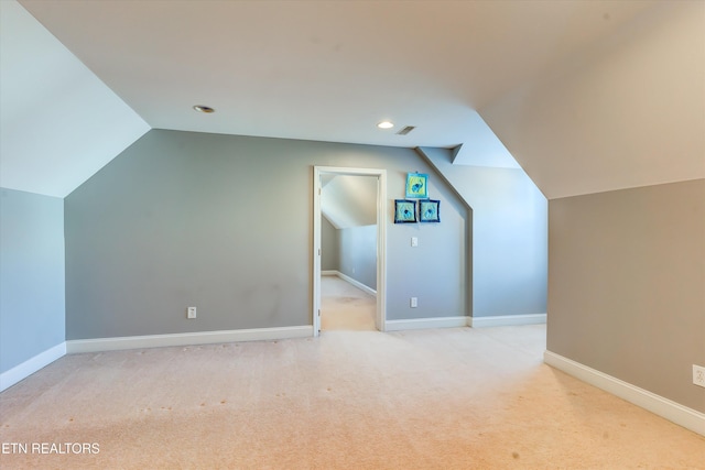 bonus room with light colored carpet and vaulted ceiling