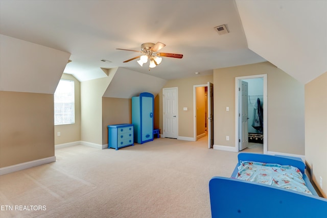 bedroom featuring ceiling fan, lofted ceiling, a walk in closet, light carpet, and a closet