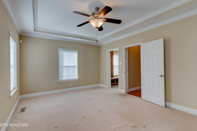 carpeted empty room featuring a raised ceiling, ceiling fan, and ornamental molding