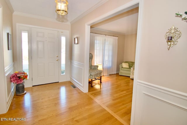 foyer entrance featuring hardwood / wood-style floors and crown molding