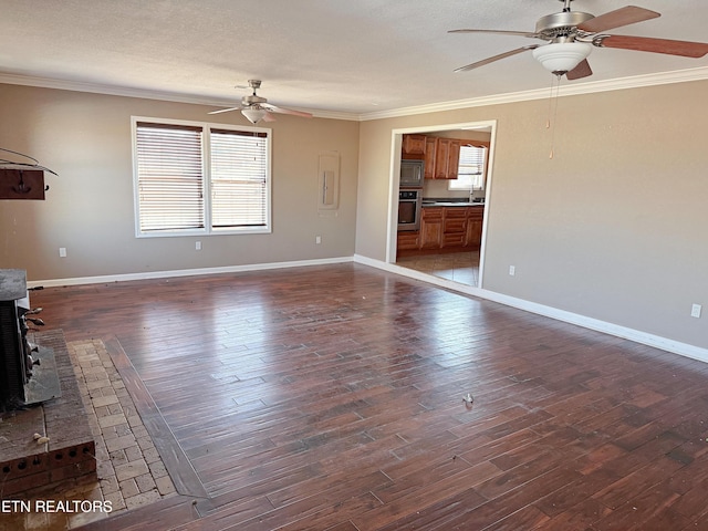 unfurnished living room with dark wood-type flooring, ceiling fan, crown molding, and a textured ceiling