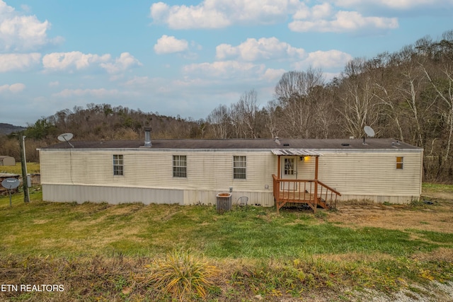 rear view of property featuring a lawn and central AC unit