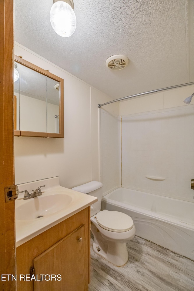 full bathroom featuring shower / bathtub combination, a textured ceiling, vanity, hardwood / wood-style flooring, and toilet