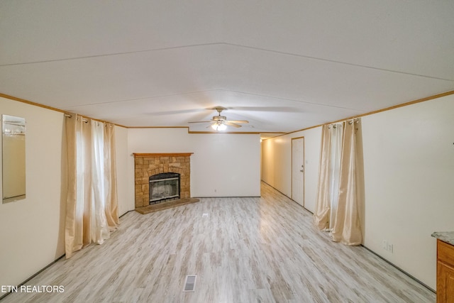 unfurnished living room with ceiling fan, a stone fireplace, and light wood-type flooring