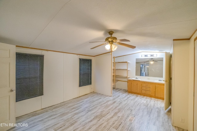 unfurnished bedroom with vaulted ceiling, ceiling fan, sink, light hardwood / wood-style floors, and a closet