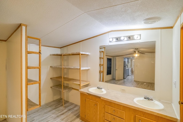 bathroom with a textured ceiling, vanity, ceiling fan, hardwood / wood-style flooring, and lofted ceiling