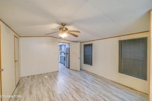 empty room with lofted ceiling, crown molding, ceiling fan, a textured ceiling, and light hardwood / wood-style floors