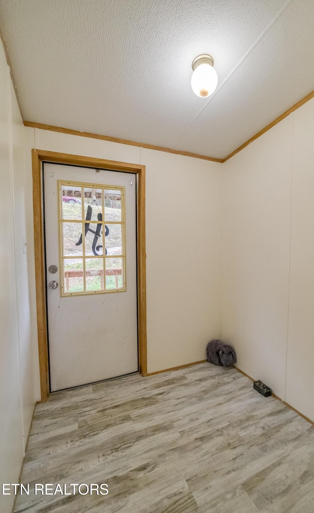 clothes washing area with crown molding, light wood-type flooring, and a textured ceiling