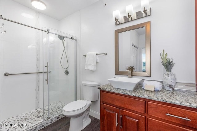 bathroom with hardwood / wood-style floors, vanity, toilet, and a shower with shower door