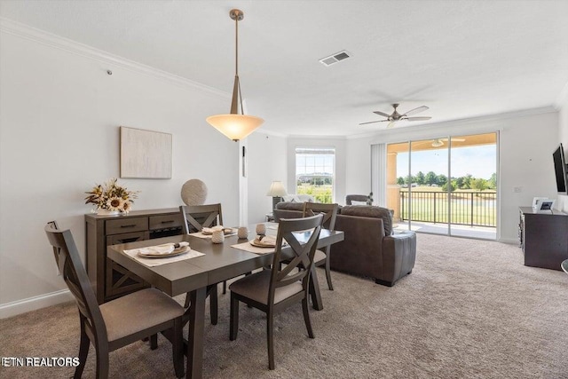 carpeted dining room with ceiling fan and ornamental molding