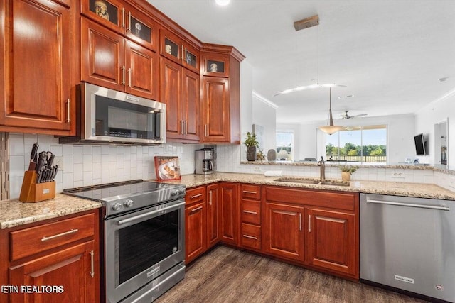 kitchen with appliances with stainless steel finishes, dark hardwood / wood-style flooring, ceiling fan, sink, and hanging light fixtures