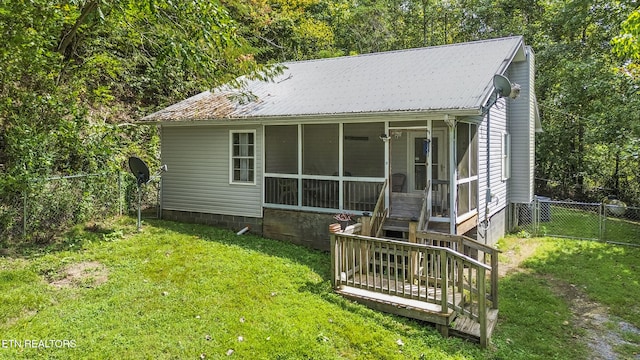 rear view of house featuring a lawn and a sunroom