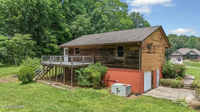 rear view of property with a garage, a wooden deck, and a yard