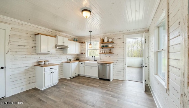 kitchen with wooden walls, wood counters, decorative light fixtures, white cabinetry, and stainless steel dishwasher