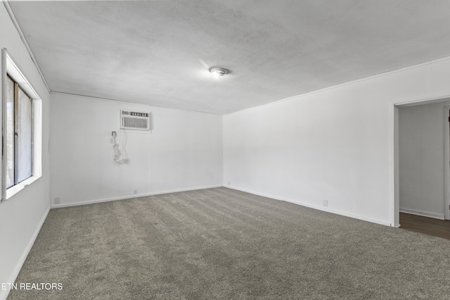 carpeted empty room featuring an AC wall unit and a textured ceiling