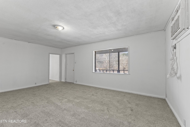 carpeted spare room featuring a wall unit AC and a textured ceiling