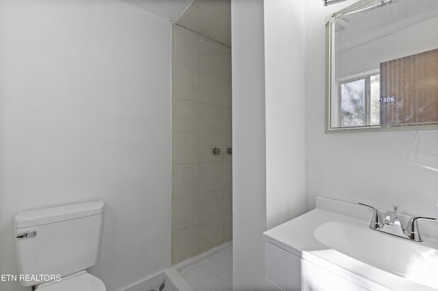 bathroom with a tile shower, vanity, and toilet