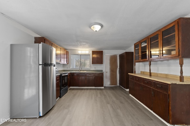 kitchen featuring sink, stainless steel fridge, dark brown cabinetry, light wood-type flooring, and black / electric stove