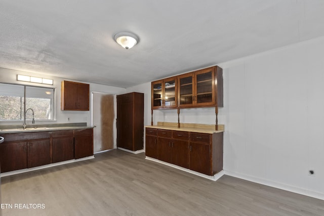 kitchen with hardwood / wood-style flooring, sink, a textured ceiling, and dark brown cabinetry