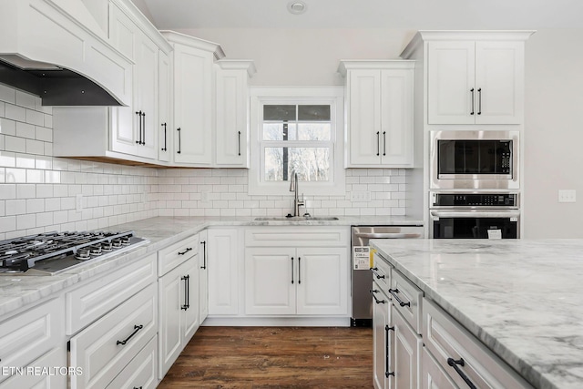 kitchen with sink, white cabinets, premium range hood, and appliances with stainless steel finishes