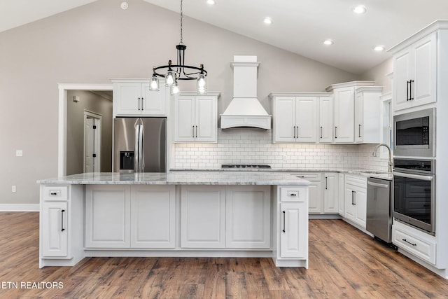 kitchen with a kitchen island, appliances with stainless steel finishes, custom exhaust hood, and decorative backsplash