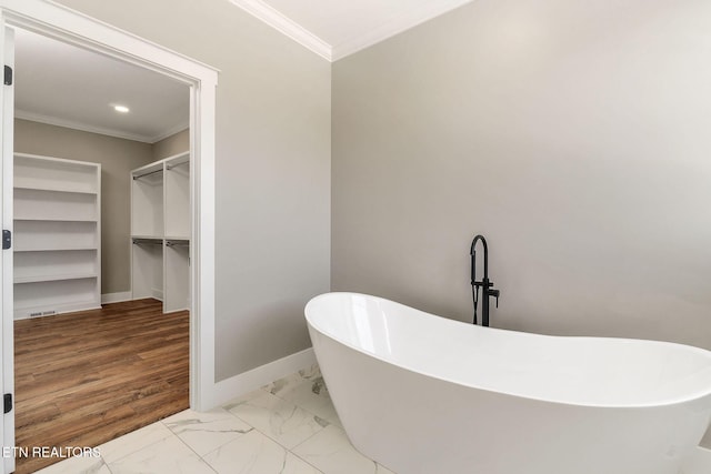 bathroom with a tub to relax in and crown molding