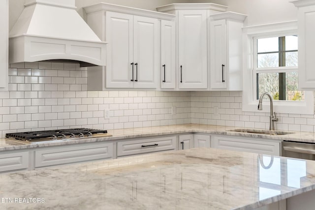 kitchen with sink, stainless steel appliances, white cabinets, tasteful backsplash, and premium range hood