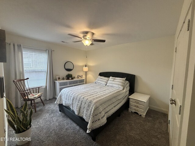 bedroom with visible vents, dark colored carpet, and a ceiling fan