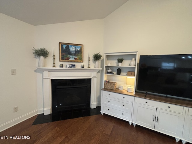 unfurnished living room featuring dark wood-type flooring, lofted ceiling, a fireplace, and baseboards