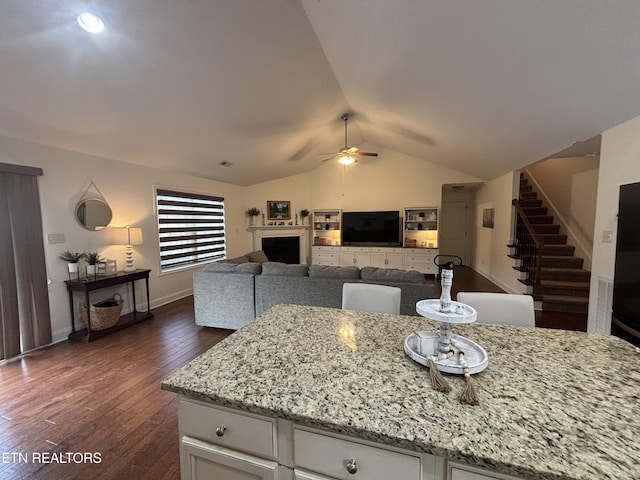 kitchen featuring white cabinetry, ceiling fan, dark wood-type flooring, lofted ceiling, and light stone counters