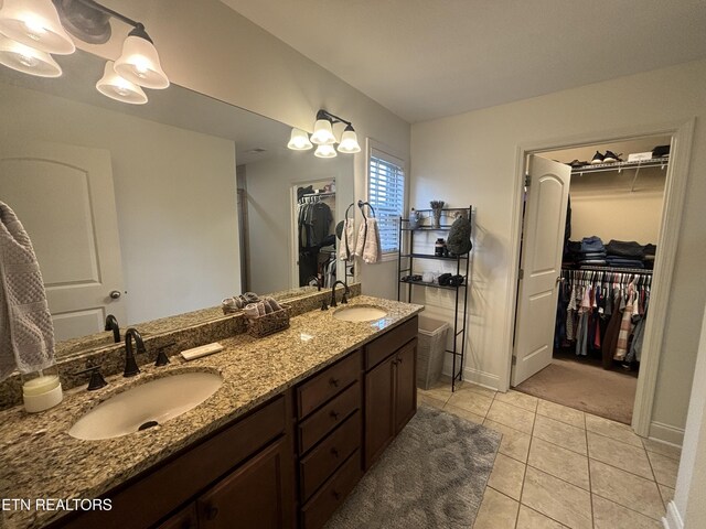 bathroom with tile patterned flooring, a sink, a spacious closet, and double vanity