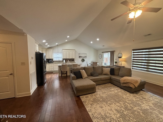 living area with dark wood-style flooring, visible vents, vaulted ceiling, and baseboards