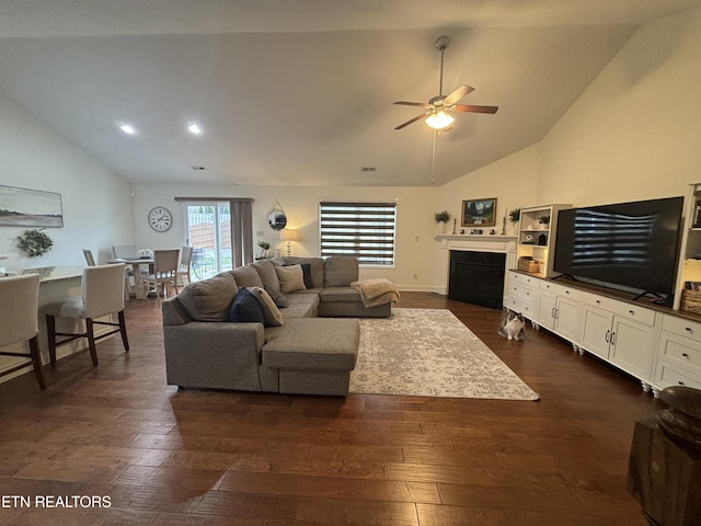 living room with ceiling fan, vaulted ceiling, and dark wood-type flooring