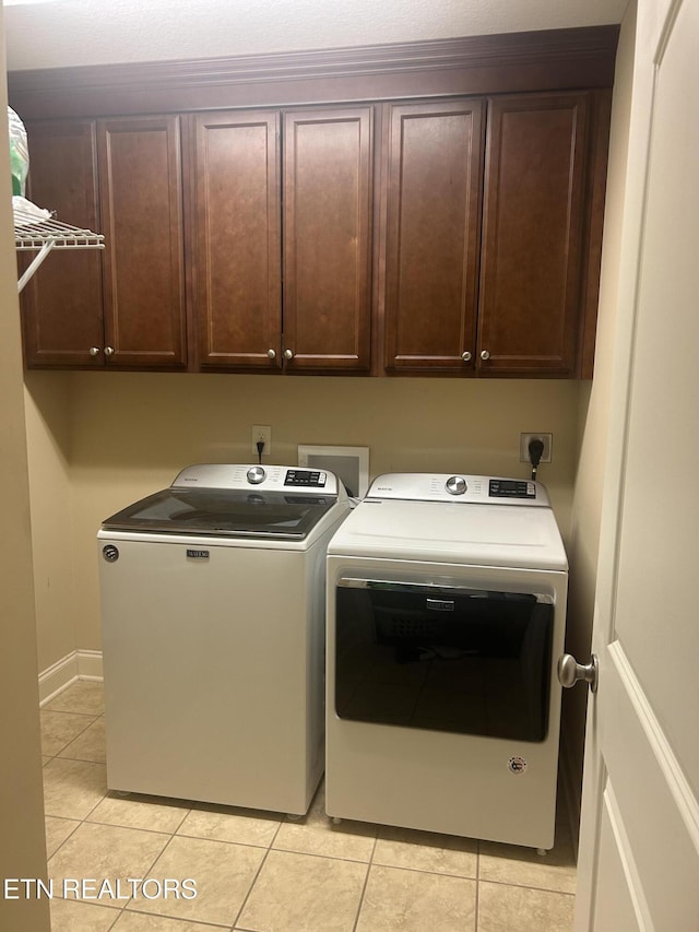 washroom with baseboards, cabinet space, washing machine and clothes dryer, and light tile patterned floors