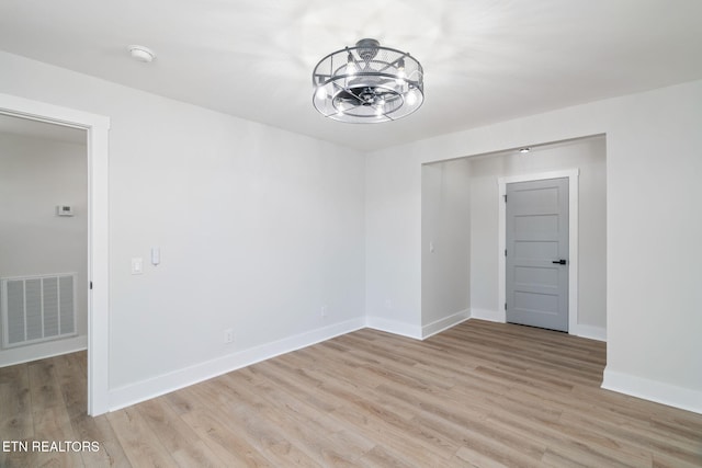 empty room with a chandelier and light hardwood / wood-style flooring