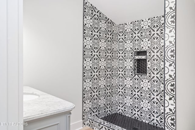 bathroom with a tile shower and vanity