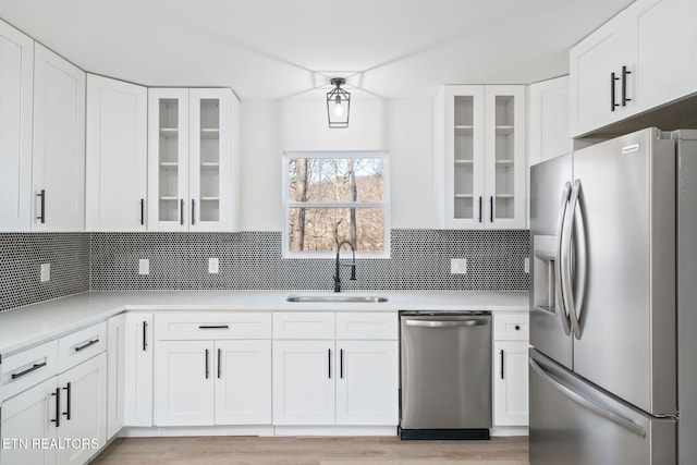 kitchen featuring decorative backsplash, sink, white cabinets, and stainless steel appliances