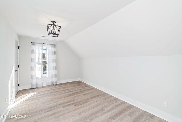 additional living space with light hardwood / wood-style flooring and lofted ceiling