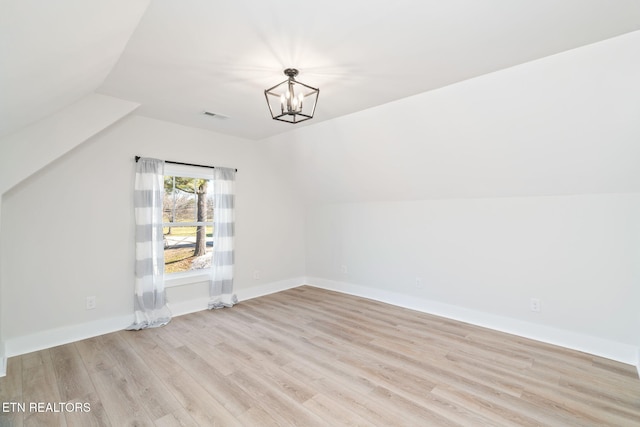 additional living space with a notable chandelier, lofted ceiling, and light wood-type flooring