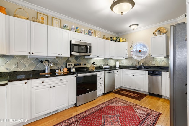 kitchen with stainless steel appliances, white cabinets, and crown molding