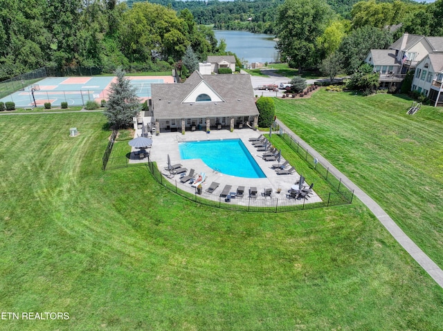 pool with a lawn, a patio area, fence, and a water view