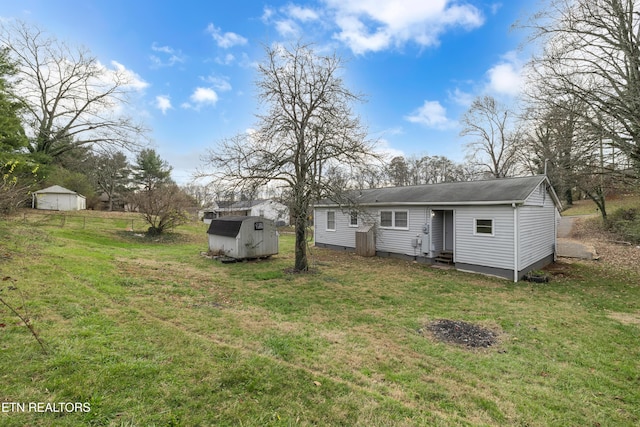 back of house with a yard and a storage unit